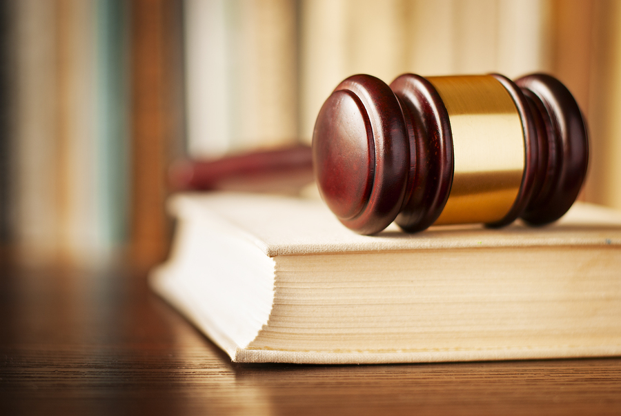 law enforcement and wooden judges gavel lying on a law book