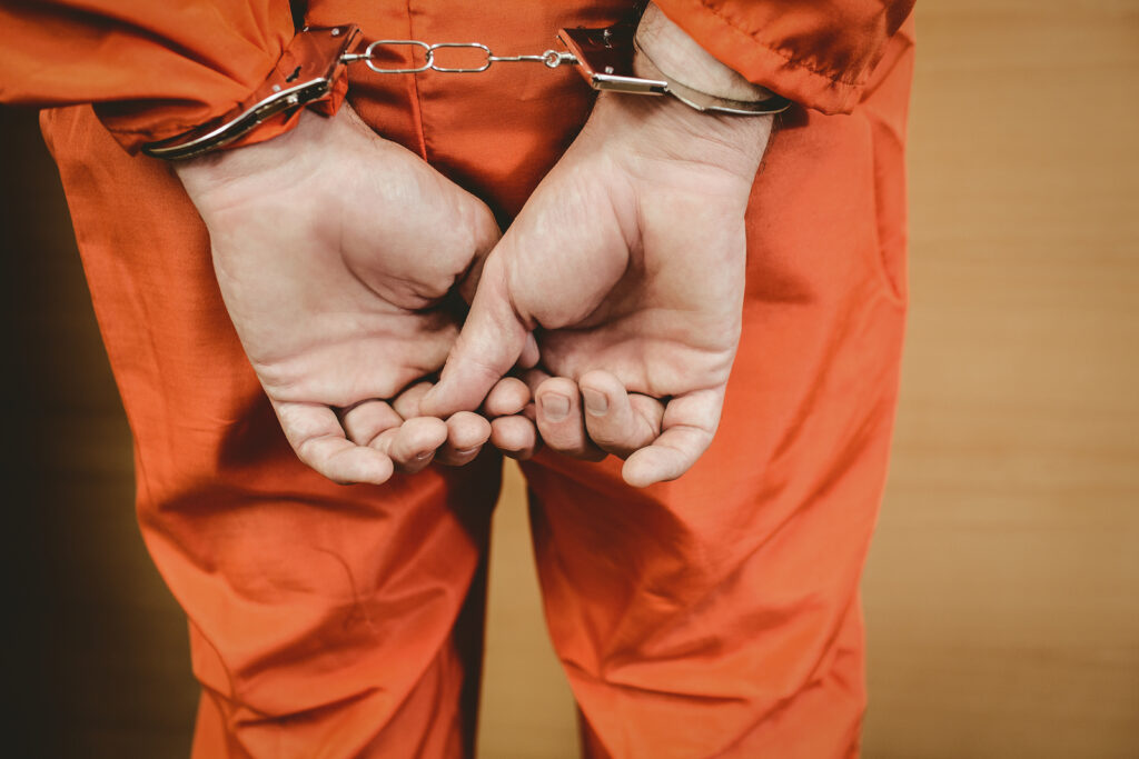 handcuffed man in orange jumpsuit