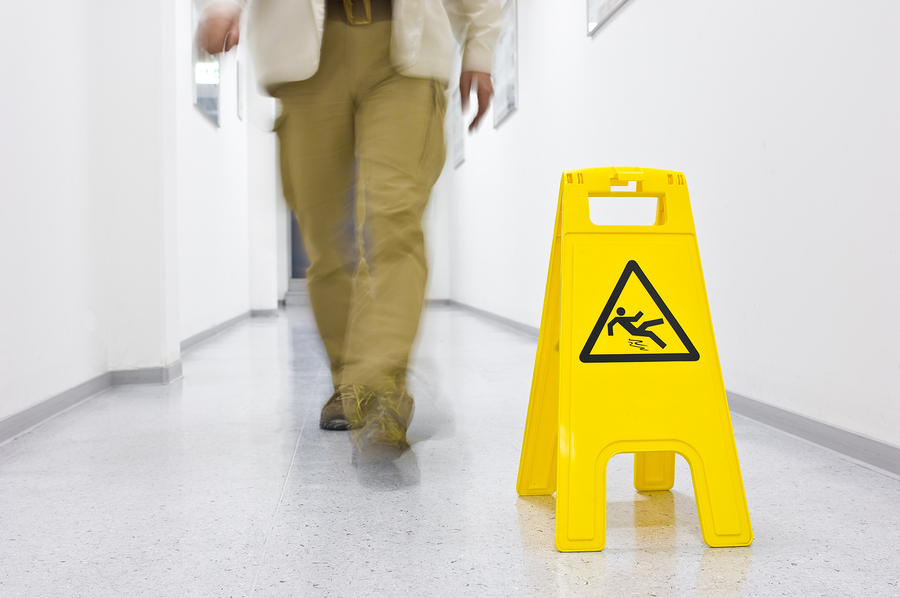 blurred man walking towards yellow slippery floor sign