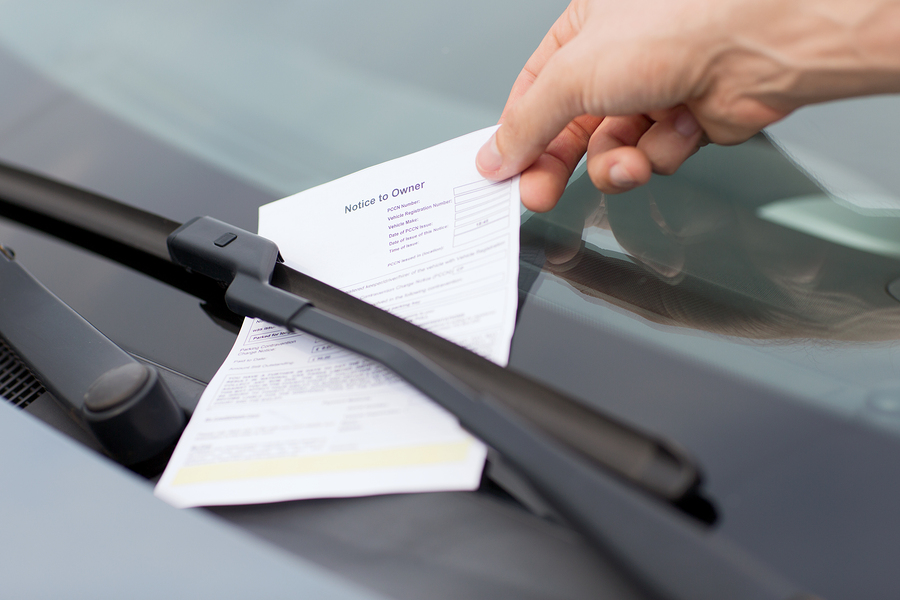 transportation and vehicle concept - parking ticket on car winds